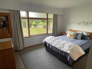 a bedroom with a bed and a large window at River Farm Retreat in Mangaweka