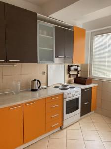 a kitchen with orange cabinets and a white stove top oven at Pastel apartment in Skopje