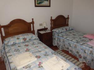 1 dormitorio con 2 camas y mesa con lámpara en Apartamento Casa Jeronimo, en Taramundi