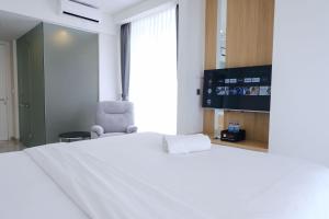 a bedroom with a large white bed and a tv at Best Deal Studio Room with Private Jaccuzi at Art Deco Apartment By Travelio in Bandung