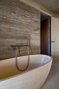 a bath tub in a bathroom with a wooden wall at 无终隅民宿 in Jizhou