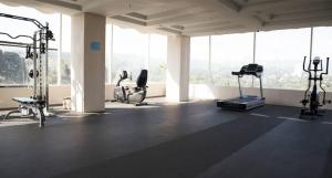 a gym with cardio equipment in a large room with windows at Best Deal Studio Room with Private Jaccuzi at Art Deco Apartment By Travelio in Bandung