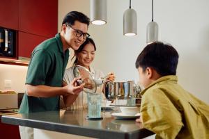 Um homem e uma mulher numa cozinha com uma criança. em Wink Icon Hotel Danang Riverside - Luxury Suites - 24hrs Stay & Rooftop Pool Bar em Da Nang
