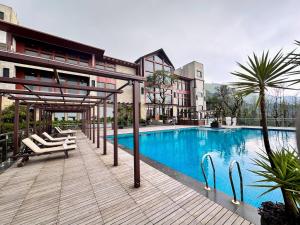 a swimming pool with lounge chairs next to a building at Trivik Hotels & Resorts, Chikmagalur in Chikmagalūr