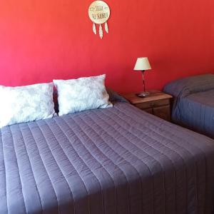 a bedroom with a bed and a red wall at Cabañas Del Alto in Villa Giardino