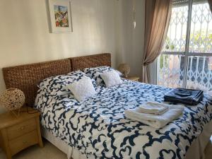 a bed with a blue and white comforter and a window at Apartment Duquesa Fairways/Manilva, Spain in Manilva +43 photos