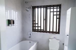 a bathroom with a tub and a toilet and a window at Luxe Oasis Villas in Lusaka +16 photos