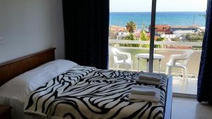 a bedroom with a zebra print bed and a view of the ocean at Pelides Apartments in Larnaca