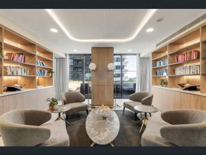 格伦韦弗利Heart of Glen Waverley Pool Gym Parking的客厅配有椅子、桌子和书架