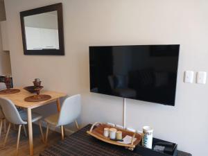 a living room with a table and a television on the wall at 106 Mossel Cove in Mossel Bay