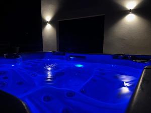 einen blauen Whirlpool in einem dunklen Raum mit Licht in der Unterkunft La Vallée des Biches G1 in Saint-Martin-Boulogne