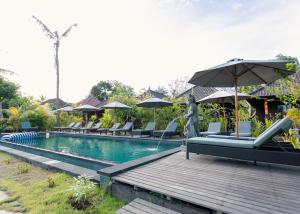 a swimming pool with lounge chairs and an umbrella at Sunset Star Huts in Nusa Lembongan