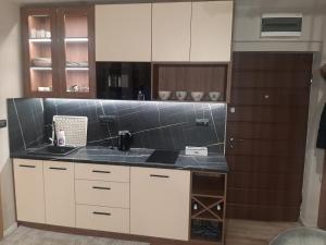 a kitchen with white cabinets and black counter tops at Jahorina Apartman in Pale +2 photos