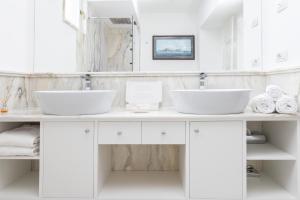 a white bathroom with two sinks and towels at Oasi Olimpia Relais in SantʼAgata sui Due Golfi +112 photos