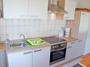 アルテフェーアにあるFerienwohnung Sundblickのキッチン(白いキャビネット、シンク、コンロ付) +15枚の写真