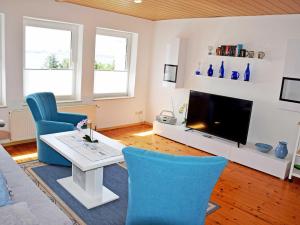 アルテフェーアにあるFerienwohnung Sundblickのリビングルーム(青い椅子、テレビ付)