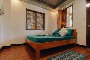 a bedroom with a bed with blue sheets and a window at Nay Carmen Pension House Port Barton in Itaytay
