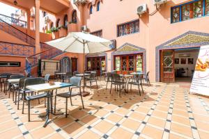 an outdoor patio with tables and chairs and an umbrella at Hotel Oudaya & Spa in Marrakech