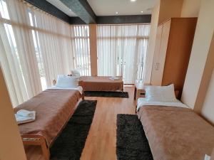 two beds in a room with large windows at Hotel Talija in Svilajnac