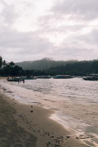 a beach with a body of water with people walking on it at Nay Carmen Pension House Port Barton in Itaytay