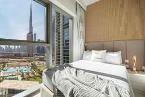 a bedroom with a bed and a large window at Dubai Mall Connected! AMAZING Burj Khalifa View! Excellent Pool & Gym Access! in Dubai +55 photos