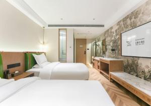 una camera d'albergo con due letti e una TV a schermo piatto di Xiamen Airport SM City Plaza Yunrui Hotel a Xiamen