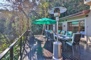 a deck with a table and a green umbrella at Cornerstone Connection in Durban