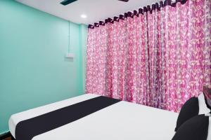 a bedroom with a bed and a pink curtain at Super Hotel O Grill Inn in Dhanbād