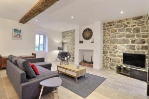 a living room with a stone wall and a tv at Château des Cours - Gîte La Providence in Taillis
