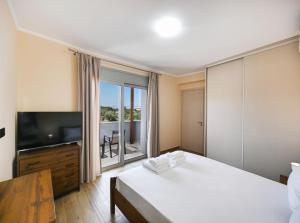 a bedroom with a bed and a flat screen tv at Villa Penelope Halipoma in Lefkada Town
