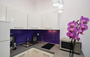 a kitchen with purple and white cabinets and a vase with purple flowers at Stunning Apartment In Rogoznica in Rogoznica