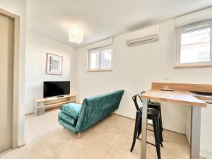 a living room with a table and a green chair at L'Esplanade - Confort & Lumineux in Mont-de-Marsan