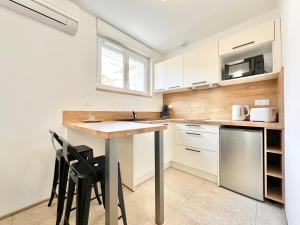 a kitchen with white cabinets and a table and chairs at L'Esplanade - Confort & Lumineux in Mont-de-Marsan