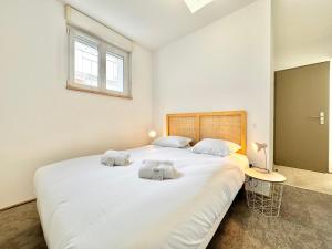 a bedroom with a large white bed with two towels on it at L'Esplanade - Confort & Lumineux in Mont-de-Marsan