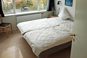 a bedroom with a bed with a white comforter and a window at Amazing Home In Rudkøbing With 6 Bedrooms And Wifi in Spodsbjerg