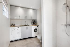 a white bathroom with a washing machine and a toilet at Holiday Home With A Wilderness Bath, Only 100 Meters From The Lovely Beach in Marielyst
