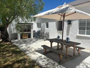 - une table de pique-nique avec un parasol sur la terrasse dans l'établissement Kandelaars Cottage, à Oudtshoorn