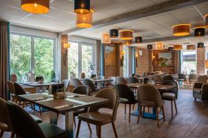 a restaurant with tables and chairs and windows at Recreatiecentrum de Kluft in Ossenzijl