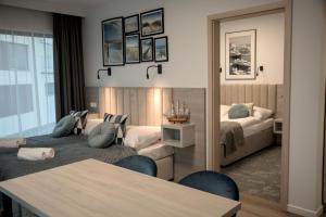 a bedroom with two beds and a table and chairs at Hotel i Apartamenty Gorzelanny Dźwirzyno in Dźwirzyno
