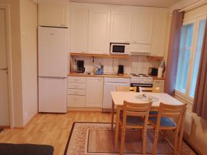 a kitchen with a table and a white refrigerator at Humppila Majoitus in Humppila