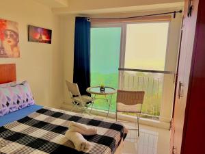 a bedroom with a bed and a balcony with a table at SMDC Wind Residences Tower 4 Taal view in Tagaytay +3 photos
