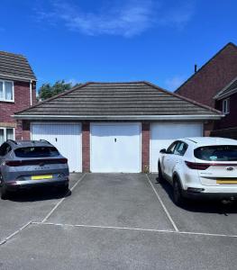 two cars parked in a parking lot in front of a garage at Contemporary House Llanelli in Llanelli