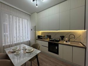 Una cocina con gabinetes blancos y una mesa con platos encima. en Arena Park, en Astana