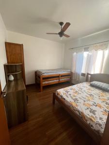 Un dormitorio con dos camas y un ventilador de techo. en Casa de praia com piscina, en Río Grande