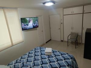 a bedroom with a bed and a tv on the wall at Condominio en Zona Privilegiada, Tranquila y Segura in Caracas