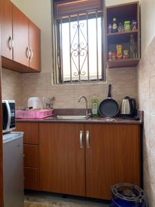 a kitchen with wooden cabinets and a sink and a window at Luxury 1 BER Apartment Bukoto in Kampala