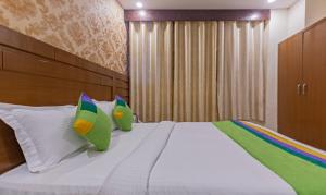 a bedroom with a bed with green and white pillows at Treebo Green View, Noida in Indirapuram +33 photos