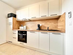 una cucina bianca con mobili bianchi e un lavello di Le Ronsard - Élégance - Central a Mont-de-Marsan