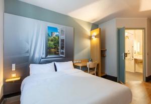 a bedroom with a large white bed and a bathroom at B&B HOTEL CHATEAUROUX Déols in Déols