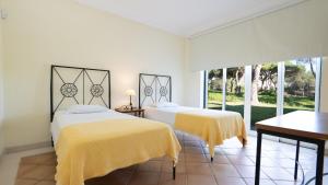 two beds in a white room with yellow sheets at Casa Atlantico in Quinta do Lago +45 photos